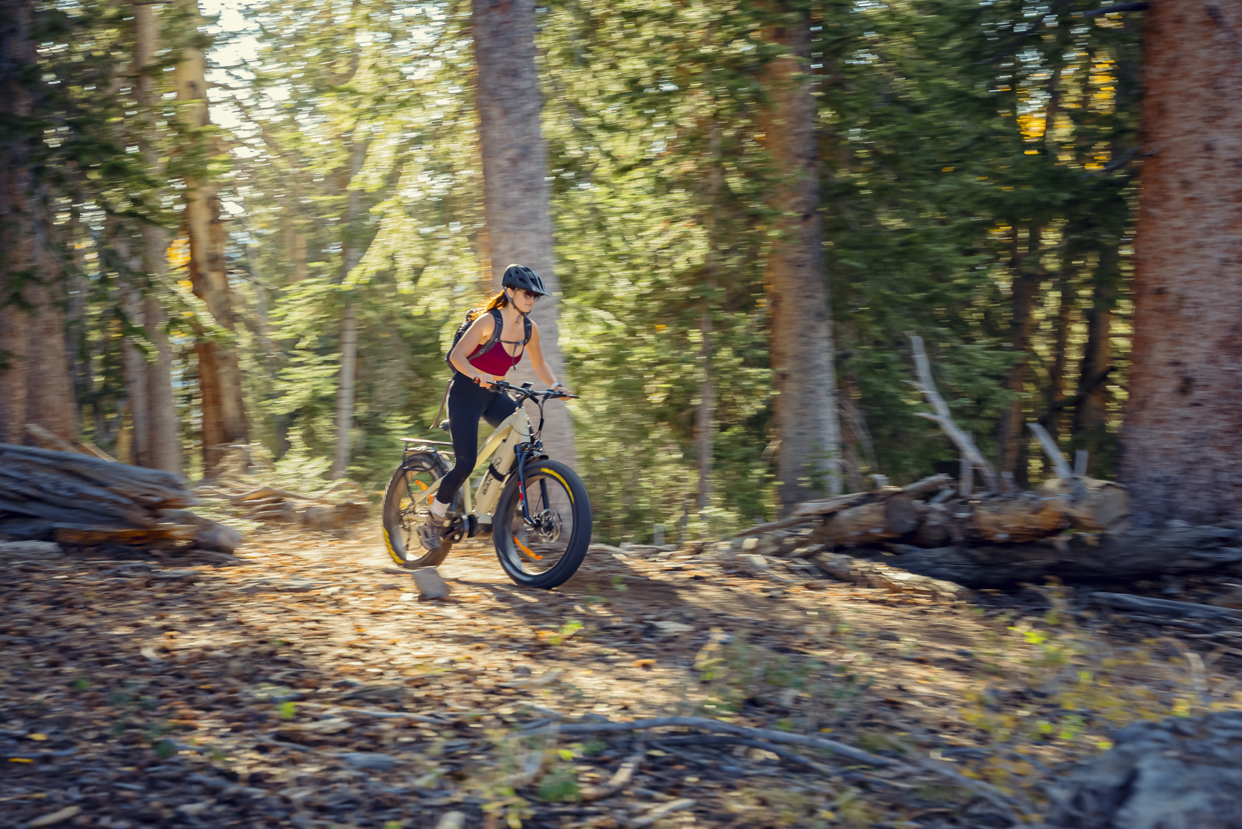 Female mountain biker riding electric bike through autumn forest with professional motion blur commercial photography