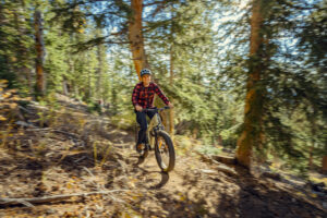 Professional mountain biker riding electric bike through forest trail with motion blur commercial photography