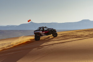 UTV climbs golden sand dunes near Sand Hollow Reservoir on a guided off-road adventure tour in Southern Utah