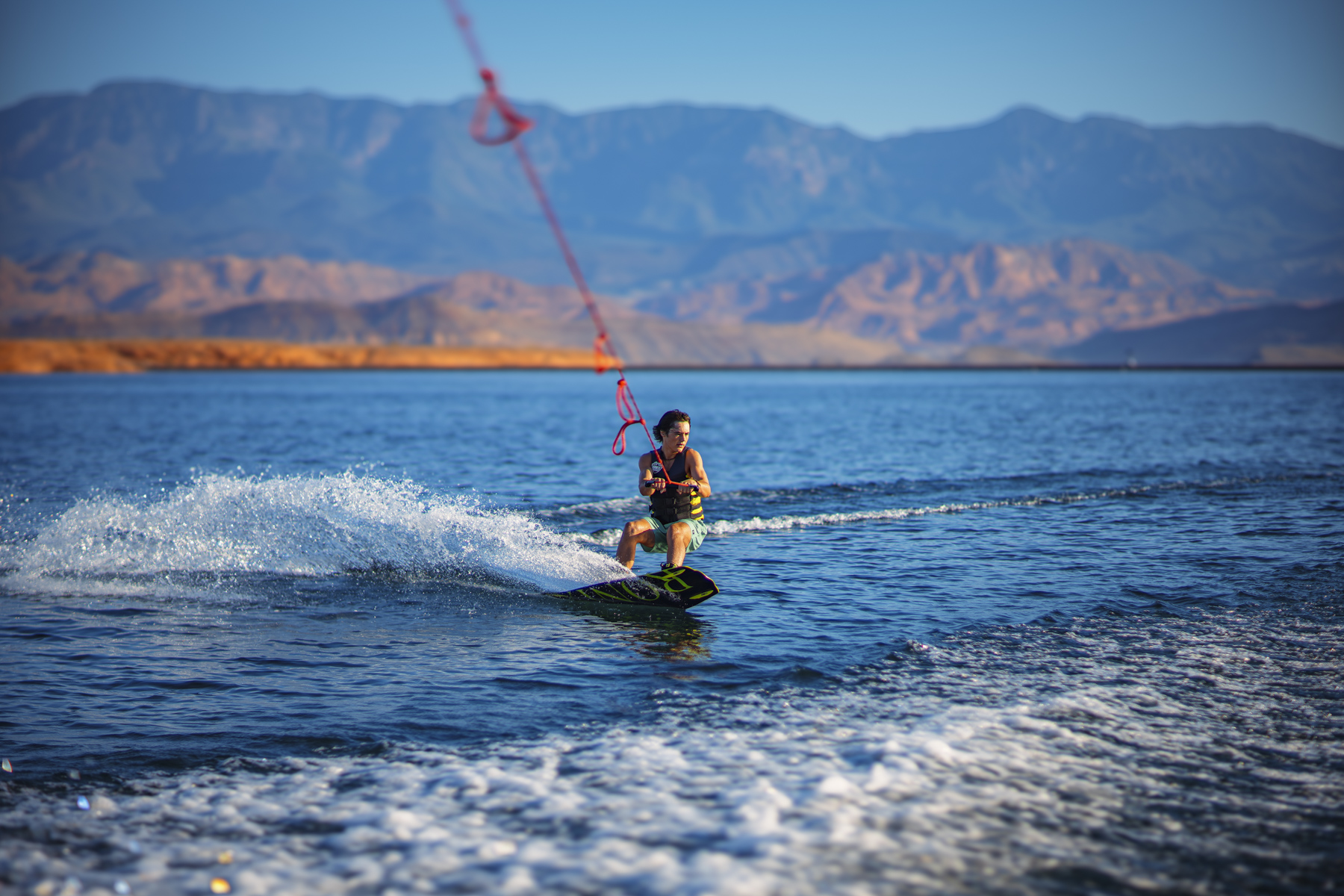 Water sports commercial photography of wakeboarding action on blue lake water with Utah desert mountain landscape captured for adventure center marketing