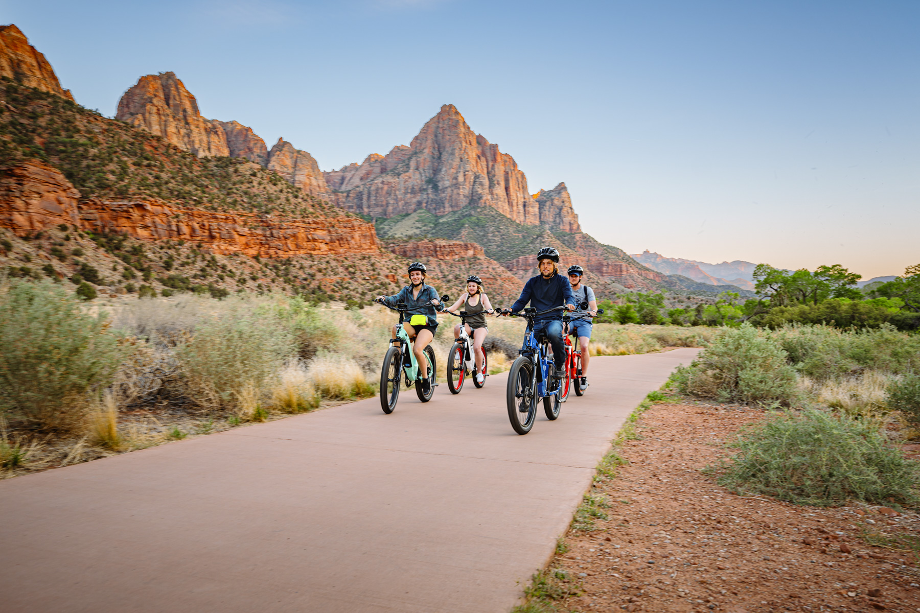Group of riders on electric bikes cruising through Zion National Park on scenic paved trail during Zion Peddler guided e-bike tour in Springdale Utah