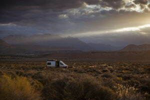 Custom Zion Van Co camper van parked in Southern Utah desert at sunset with dramatic light and mountain backdrop