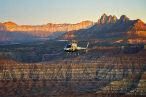 Commercial helicopter flying through Zion valley during sunset showcasing aviation tourism marketing and professional commercial photography services