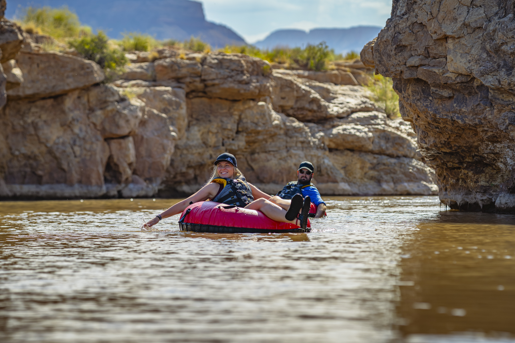 Two guests floating through a canyon corridor on the river near Zion, photographed for adventure hospitality marketing.
