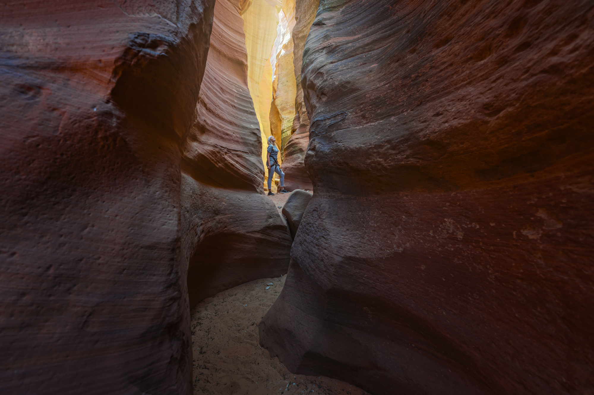 Wide view of a winding slot canyon with a lone explorer in the distance, built as adventure brand photography and lifestyle photography for brands.